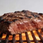 Grosse tranche de viande roussie sur grille incandescente.