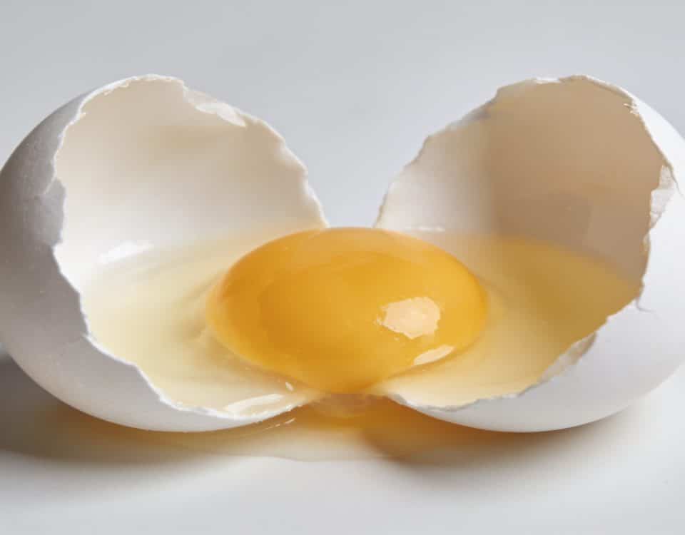 Oeuf blanc casse en deux montrant le jaune intact