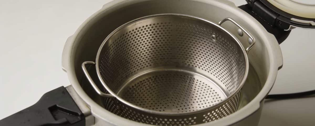 Panier metallique ajoure positionne dans cocotte minute ouverte.