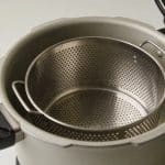 Panier metallique ajoure positionne dans cocotte minute ouverte.