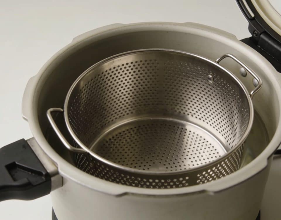 Panier metallique ajoure positionne dans cocotte minute ouverte.