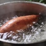 Patate douce entière dans casserole d'eau bouillante.