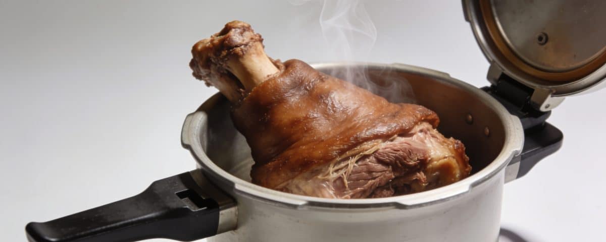 Pied de porc bruni dans cocotte-minute ouverte, vapeur montante