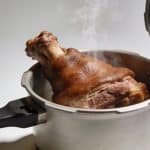 Pied de porc bruni dans cocotte-minute ouverte, vapeur montante