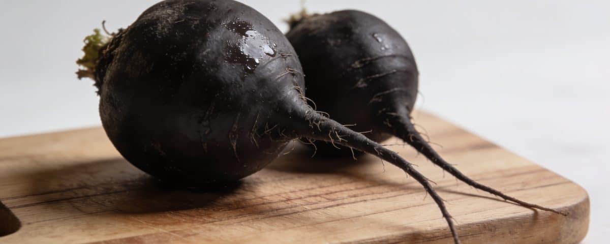 Radis noirs entiers posés sur planche bois cuisine