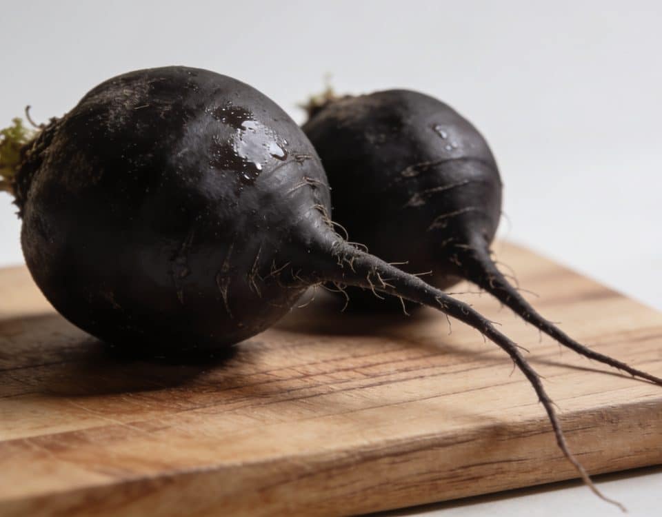 Radis noirs entiers posés sur planche bois cuisine