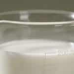Verre gradué contenant liquide blanc mesurant deux cents millilitres
