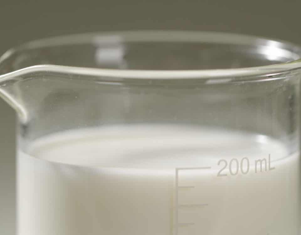 Verre gradué contenant liquide blanc mesurant deux cents millilitres